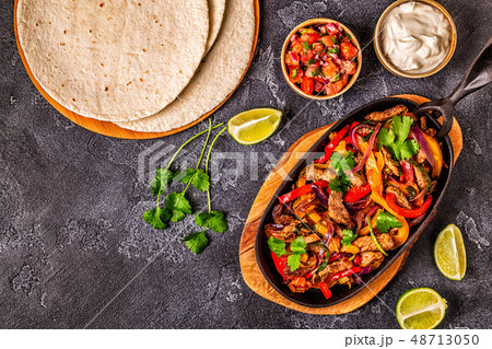 FAJITAS with colored pepper and onions, served FAJITAS with colored pepper and onions, served 48713050