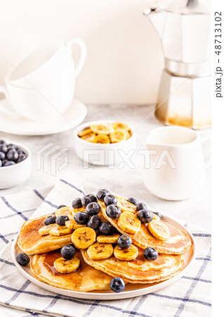 Pancakes with banana,  blueberries on white plate. 48713102