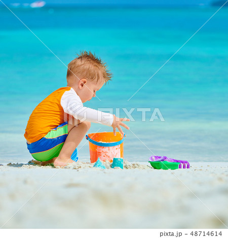 Three year old toddler playing on beach Three year old toddler playing on beach 48714614