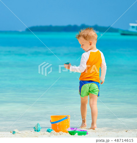 Three year old toddler playing on beach Three year old toddler playing on beach 48714615