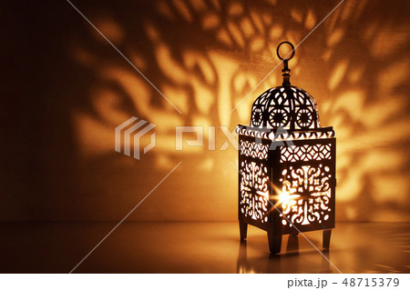 Silhouette of Moroccan ornamental lantern with burning glowing candle. Decorative shadows. Festive 48715379