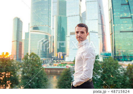 Businessman looking on copy space while standing against glass skyscraper Businessman looking on copy space while standing against glass skyscraper 48715624