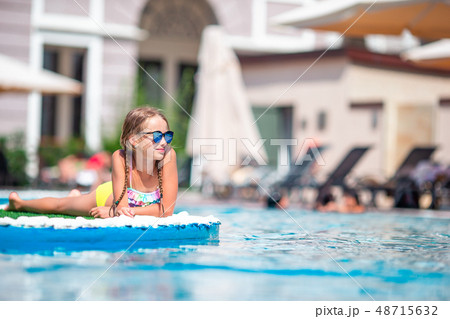 Beautiful little girl having fun near an outdoor pool Beautiful little girl having fun near an outdoor pool 48715632