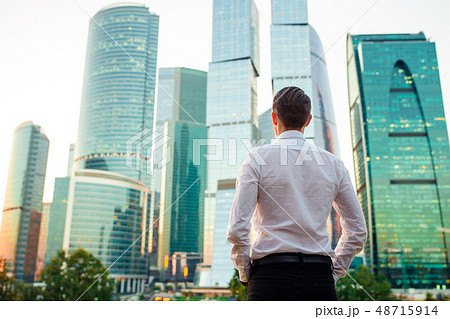 Back view of businessman looking on copy space while standing against glass skyscraper 48715914