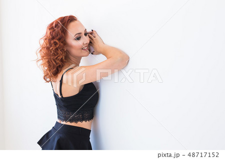 People and fashion concept - Redhead woman in black shirt and skirt posing isolated on white 48717152