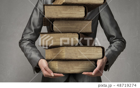 Woman carrying stack of books 48719274