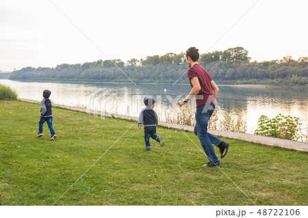 Childhood, family concept - father playing with two sons near the lake Childhood, family concept - father playing with two sons near the lake 48722106
