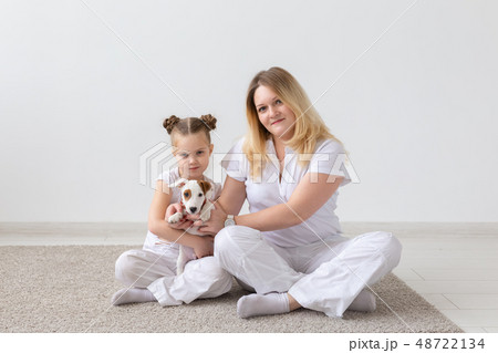 people, family and pets concept - mother and daughter sitting on the floor with puppy Jack Russell people, family and pets concept - mother and daughter sitting on the floor with puppy Jack Russell 48722134