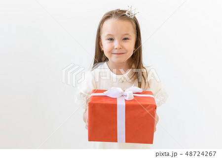 people, children and holiday concept - portrait of happy little girl holding a gift box over white people, children and holiday concept - portrait of happy little girl holding a gift box over white 48724267