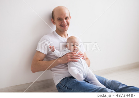 Children, family and fatherhood concept - happy bald father holding baby daughter on knees on white Children, family and fatherhood concept - happy bald father holding baby daughter on knees on white 48724487
