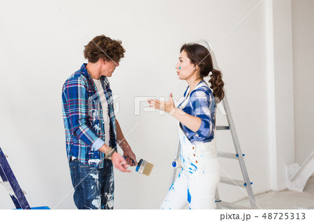 Conflict, redecoration, renovation and people concept - a couple doing a repair in apartment and 48725313