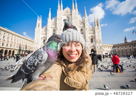 Winter travel, vacations and birds concept - Young happy woman tourist with funny pigeons making Winter travel, vacations and birds concept - Young happy woman tourist with funny pigeons making 48726327