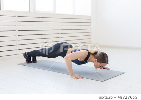 People, sport and fitness concept - young beautiful sportswoman doing push ups People, sport and fitness concept - young beautiful sportswoman doing push ups 48727655