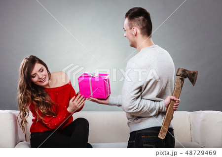 Insincire man holding axe giving gift box to woman 48729469