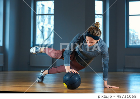 Fit and muscular woman doing intense core workout with kettlebell in gym. Female exercising at 48731068