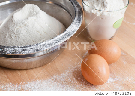 Flour in bowl and two eggs on wooden table background Flour in bowl and two eggs on wooden table background 48733108