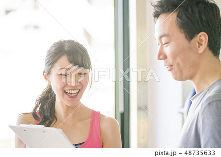 パーソナルジムの女性インストラクターから食事のメニューを見せられ栄養バランスの説明を受ける男性 パーソナルジムの女性インストラクターから食事のメニューを見せられ栄養バランスの説明を受ける男性 48735633