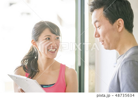 女性インストラクターからトレーニングメニューを見せられ驚く男性 女性インストラクターからトレーニングメニューを見せられ驚く男性 48735634