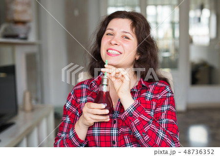 Detox, diet and healthy lifestyle concept - young woman holds a bottle of fresh juice 48736352