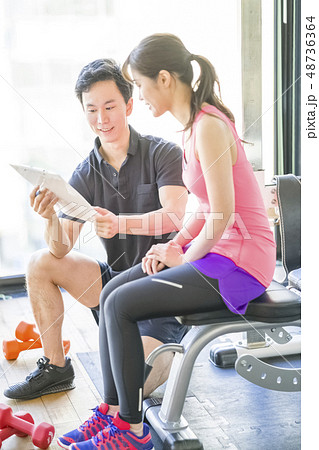 パーソナルジムで継続的にダイエットする女性の相談に乗るイケメン男性インストラクター 48736364