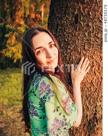 Portrait beautiful smiling caucasian brunette girl with long hair in the forest at sunset leaned 48736579