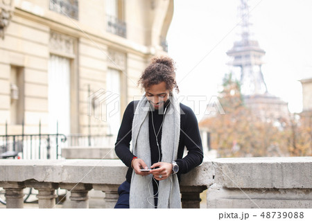 guy enjoying smartphone and earphones with Eiffel tower guy enjoying smartphone and earphones with Eiffel tower 48739088
