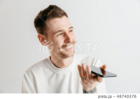 Indoor portrait of attractive young man holding smartphone 48740376