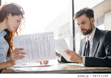 Businesspeople having business lunch at restaurant sitting looking at documents concentrated 48741190