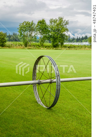 Green lawn with irrigation system over the field on cloudy summer day 48747401