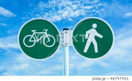 Bicycle and pedestrian shared route sign on cloudy sky background. Bicycle and pedestrian shared route sign on cloudy sky background. 48747451