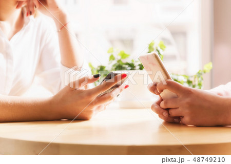 Female hands with smartphones close-up in cafe. 48749210