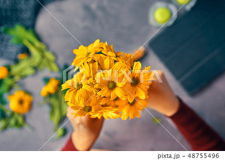 Woman puts a yellow flowers in vase 48755496