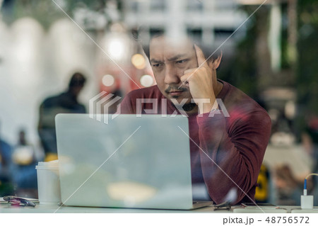 Portrait of asian businessman in casual suit using technology laptop for working in serious and exhausted action at the desk beside the glass in modern office,Business and lifestyle concept 48756572
