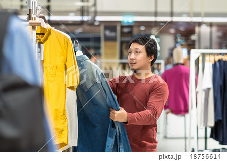 Smart asian man with beard choosing clothes in clothing store at shopping center, Compare the differences between shirts, Fashion, Style and Consumerism Concept. Smart asian man with beard choosing clothes in clothing store at shopping center, Compare the differences between shirts, Fashion, Style and Consumerism Concept. 48756614