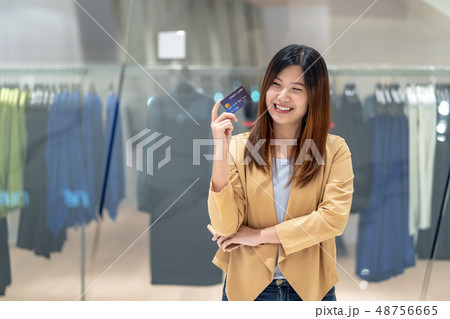 Asian woman using credit card with mobile phone for online shopping in department store over the clothes shop store background, technology money wallet and online payment concept, credit card mockup Asian woman using credit card with mobile phone for online shopping in department store over the clothes shop store background, technology money wallet and online payment concept, credit card mockup 48756665