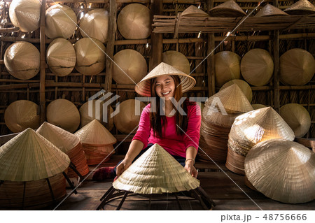 Asian traveler female craftsman making the traditional vietnam hat in the old traditional house in Ap Thoi Phuoc village, Hochiminh city, Vietnam, traditional artist concept 48756666