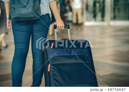 Closeup hand holding the luggage over the flight board for check-in at the flight information screen in modern an airport, travel and transportation concept 48756687