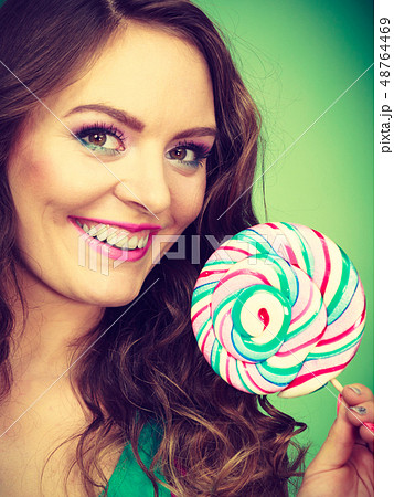 Smiling girl with lollipop candy on green 48764469