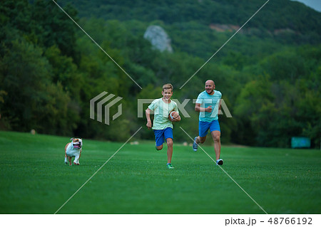 Father and son are running in park with dog Father and son are running in park with dog 48766192