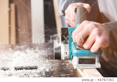 The hands of a carpenter working woodworking power tools. Close up of the work of the electric 48767361