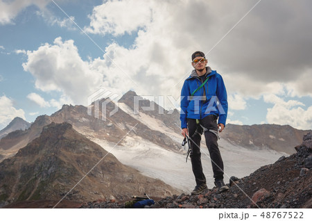 Portrait of a professional guide of a mountaineer in a cap and sunglasses with an ice ax in his hand 48767522