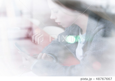 Portrait of a young girl sitting in a cafe outside the window with a reflection of the street 48767667