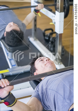 ボディービルの大会に向けトレーニングジムで真剣な表情でベンチプレスをする若い男性細マッチョ 48768066