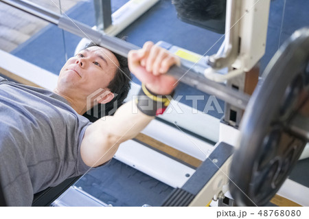 トレーニングジムで真剣な表情でベンチプレスをするストイックな若い男性細マッチョ トレーニングジムで真剣な表情でベンチプレスをするストイックな若い男性細マッチョ 48768080