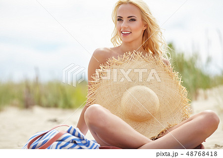 Naked woman on the beach holding summer hat - Stock Photo 48768418