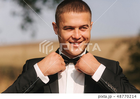 Handsome groomm dressed a tie bow. Wedding day. Man outside Handsome groomm dressed a tie bow. Wedding day. Man outside 48770214