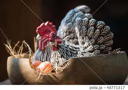 Clay hen and egg in wood basket. Clay hen and egg in wood basket. 48771317