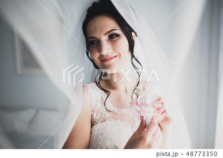 Gorgeous bride in robe posing and preparing for the wedding ceremony face in a room Gorgeous bride in robe posing and preparing for the wedding ceremony face in a room 48773350