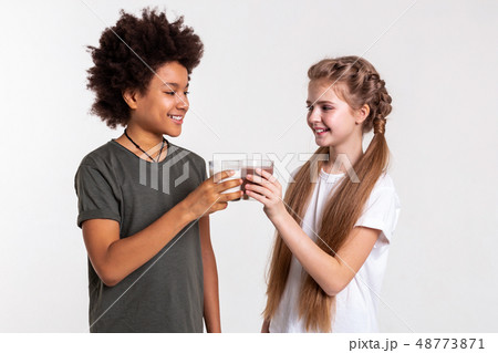 Cheerful appealing kids clinking glasses filled with sweet drinks Cheerful appealing kids clinking glasses filled with sweet drinks 48773871