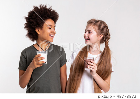 Pleasant laughing children wearing t-shirts and standing closely together 48773872